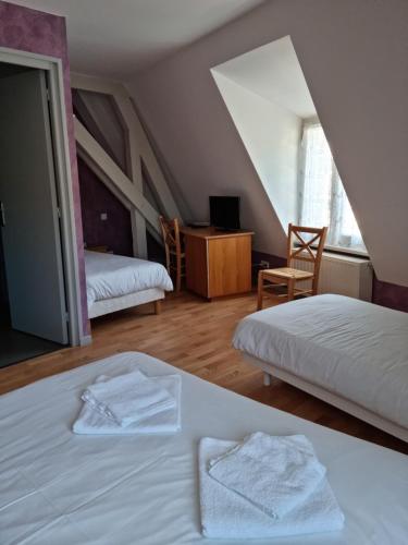 a bedroom with two beds with white sheets and a table at Auberge le Cheylet in Apchon