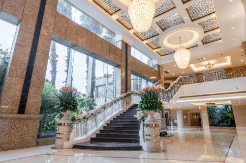 a lobby with a staircase with potted plants at Maritim Hotel Taicang Garden in Taicang