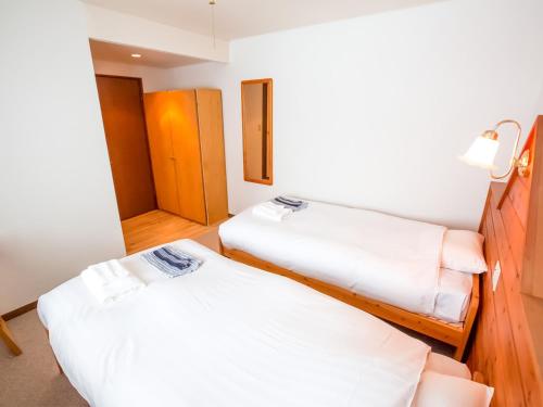 two beds in a room with white sheets at Rusutsu Lodges Pension Lilla Huset in Rusutsu