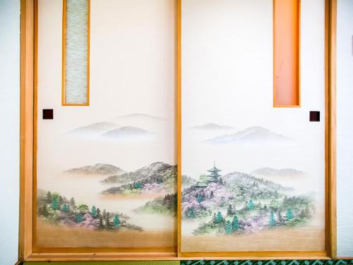 a pair of paintings on a window with mountains at Rusutsu Lodges Pension Lilla Huset in Rusutsu