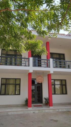 een wit gebouw met rode zuilen en een balkon bij Dakghar 606 in Khajurāho