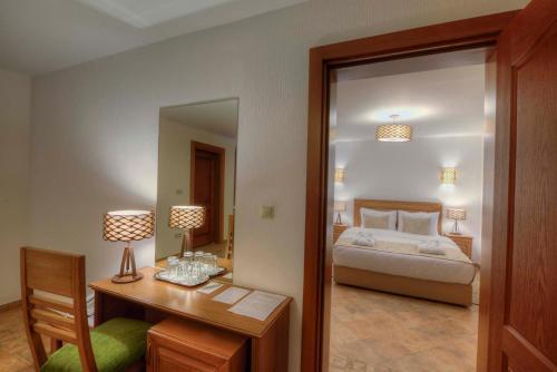 a bedroom with a bed and a desk and a mirror at RIVER INN RESORT AND SPA in Nabran