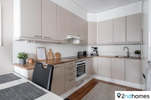 eine weiße Küche mit weißen Schränken und einem schwarzen Stuhl in der Unterkunft Homelike 1BR Apartment with Sauna, Balcony & Free Parking in Tampere