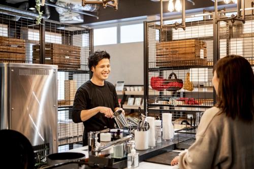 a man preparing food in a kitchen with a woman at EIGHT POINT INN Kanazawa in Kanazawa