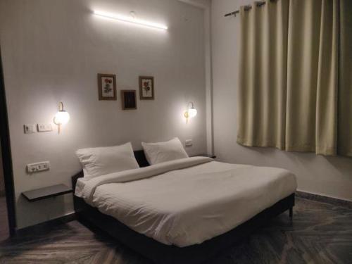 een slaapkamer met een groot bed met witte lakens bij Dakghar 606 in Khajurāho