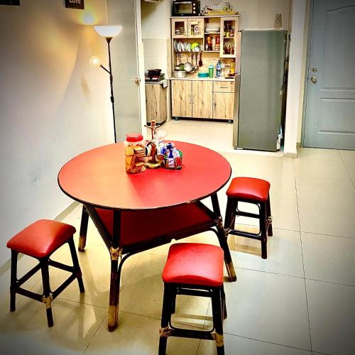 a table with four chairs and a red table and a kitchen at Monkey Mansion in Kuala Lumpur