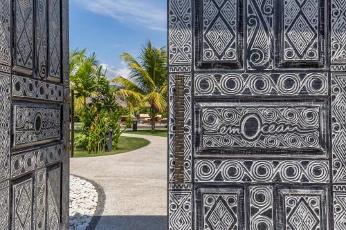 ein Paar Türen auf einem Gebäude mit Palmen im Hintergrund in der Unterkunft Emocean Beach Boutique Dive Resort in Amed