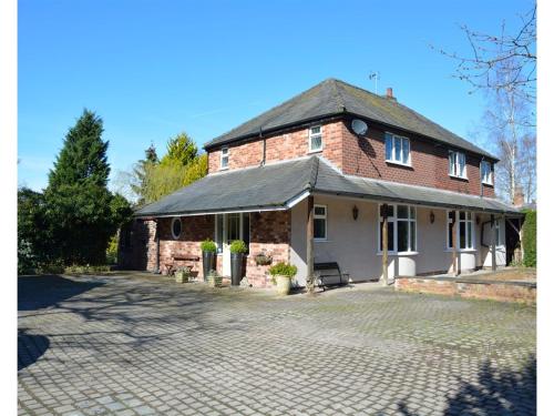 a brick house with a driveway in front of it at Laburnum Cottage Guest House in Knutsford