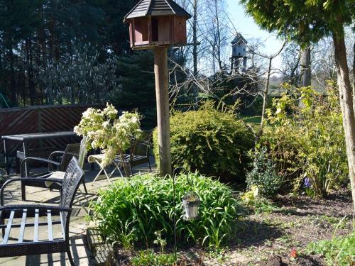 une maison ornithologique et un banc dans un jardin dans l'établissement Laburnum Cottage Guest House, à Knutsford
