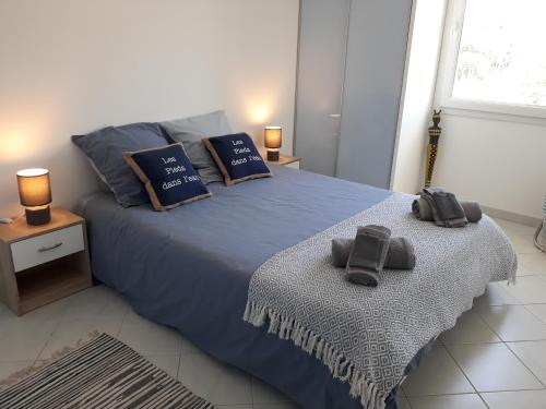 - une chambre avec un lit bleu et 2 chaussons dans l'établissement Joli T3 lumineux confortable et idéale situation, à Cavalaire-sur-Mer