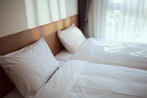 two white beds in a bedroom with a window at Kenny Stay Busan Gijang in Busan