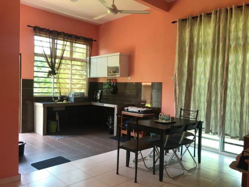 a kitchen with orange walls and a table and chairs at Homestay Tok Penghulu in Kuantan