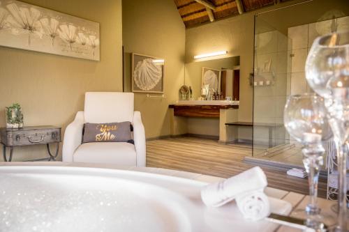 a bathroom with a tub and a chair and glasses at Kambaku River Sands in Timbavati Game Reserve