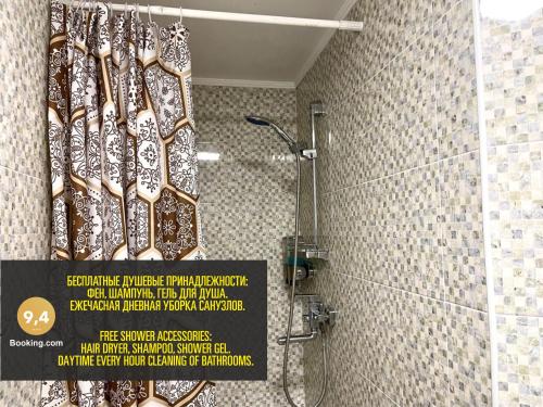 a bathroom with a shower with a sign on the wall at LES Mini Hotel in Almaty
