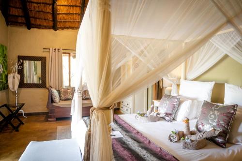 a bedroom with a canopy bed with pillows at Kambaku Safari Lodge in Timbavati Game Reserve