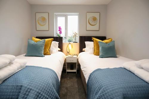 Duas camas num quarto com almofadas azuis e amarelas em Aisiki Apartments at Stanhope Road, North Finchley, 3 Bedroom and 2 Bathroom Pet Friendly Duplex Flat, King or Twin beds with FREE WIFI em Finchley