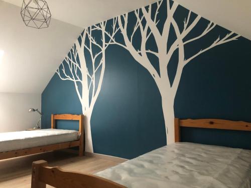 ein Schlafzimmer mit einem Wandbild von Bäumen in der Unterkunft Maison chaleureuse à la campagne in Camps-en-Amiénois