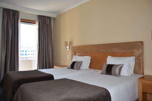 a hotel room with two beds and a window at QH Praia de Quiaios in Praia de Quiaios