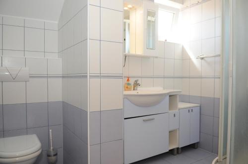 a white bathroom with a toilet and a sink at Apartmani Kristiana in Jezera
