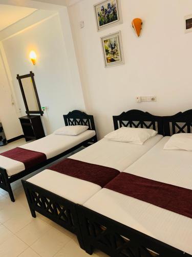 two beds in a room with white and red at Sethway Village in Minneriya
