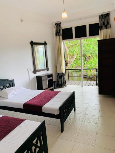 a bedroom with two beds and a large window at Sethway Village in Minneriya