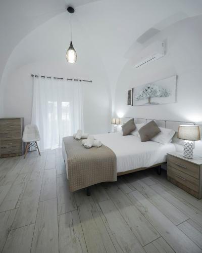 a white bedroom with a large bed and wooden floors at Apartamentos Gladiador in Merida