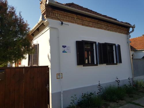 ein weißes Haus mit schwarzen Fenstern und einem Holztor in der Unterkunft Garden House Vendégház in Bükkszék