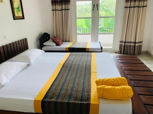 two beds in a room with two windows at Sethway Village in Minneriya