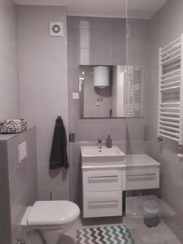 a white bathroom with a toilet and a sink at Elena apartmani Tuzla in Tuzla
