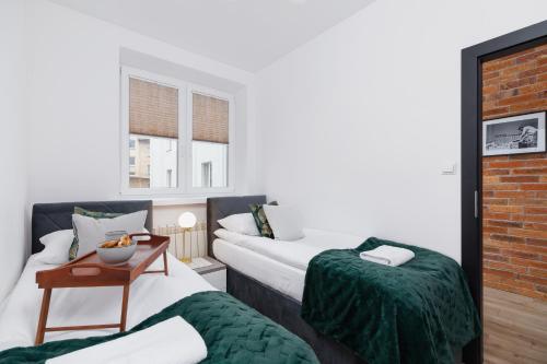 pokój hotelowy z dwoma łóżkami i stołem w obiekcie Apartments Osiedle Szkolne Cracow by Noclegi Renters w Krakowie