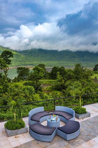 a patio with two blue chairs and a table at SaffronStays Sundowner by the Lake, Karjat - party-perfect pool villa with rain dance and cricket turf in Karjat