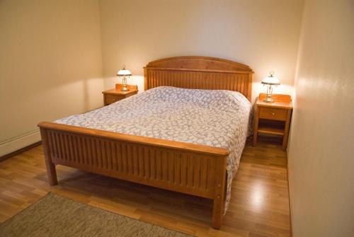 een slaapkamer met een houten bed met 2 nachtkastjes bij Hotel Kiteenhovi in Kitee