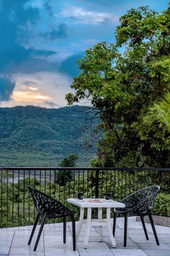 a table and two chairs on a patio with a view at SaffronStays Sundowner by the Lake, Karjat - party-perfect pool villa with rain dance and cricket turf in Karjat
