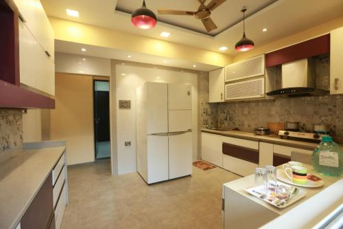 a kitchen with white cabinets and a white refrigerator at Villa Residency in Navi Mumbai