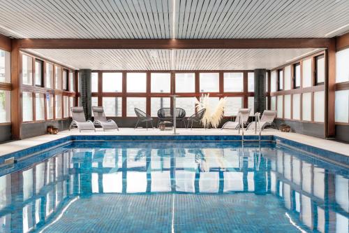 a large swimming pool with chairs and a table at Hotel Imperiale Rimini & SPA in Rimini