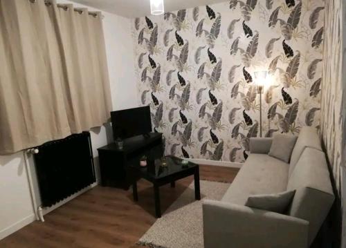 - un salon avec un canapé et un mur à motifs ornés d'oiseaux dans l'établissement Joli T2 près de Rennes, à Vezin-le-Coquet