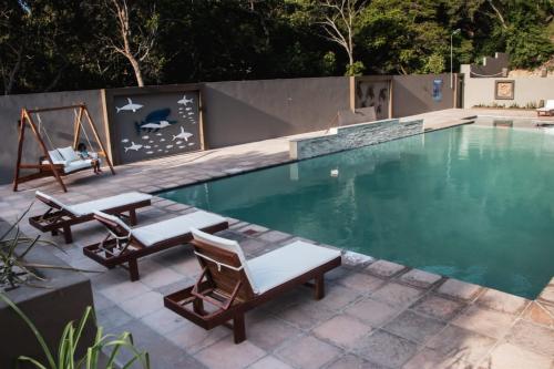 a swimming pool with two chairs and a swing at WHITE SHARK RESORT in Ponta do Ouro