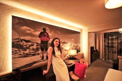 a woman standing in a hotel room with a painting on the wall at Die Seefelderin - Boutiquehotel St. Georg in Seefeld in Tirol