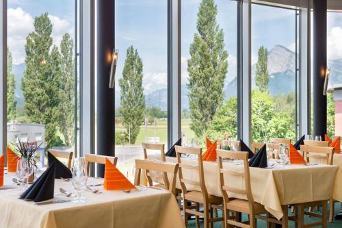 a dining room with tables and chairs and windows at Swiss Heidi Hotel in Maienfeld
