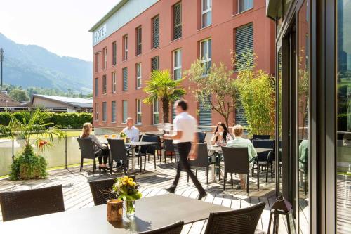 a man walking on a patio with people sitting at tables at Swiss Heidi Hotel in Maienfeld