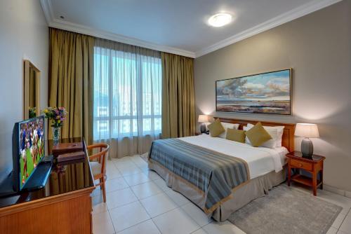 Habitación de hotel con cama y TV en Al Nakheel Hotel Apartments Abu Dhabi, en Abu Dabi