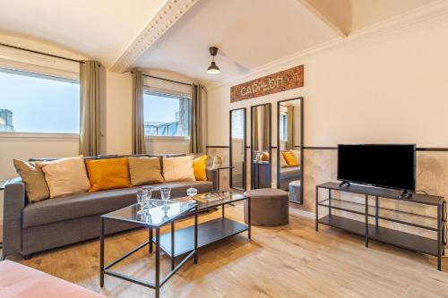 ein Wohnzimmer mit einem Sofa und einem TV in der Unterkunft KASA du Moulin - Cosy et au calme in Saint-Quentin