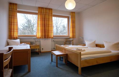 a hotel room with two beds and two windows at St. Bonifatiuskloster - Geistliches Zentrum in Hünfeld