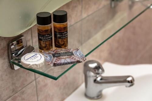 a bathroom sink with two bottles of essential oils on a shelf at Telis Hotel in Aigio
