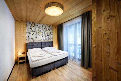 a bedroom with a large bed with a stone wall at Apartmany Demänovka in Demanovska Dolina