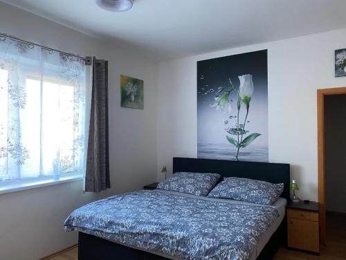 1 dormitorio con 1 cama con una pintura floral en la pared en Apartman c.8 Magnolie en Třeboň
