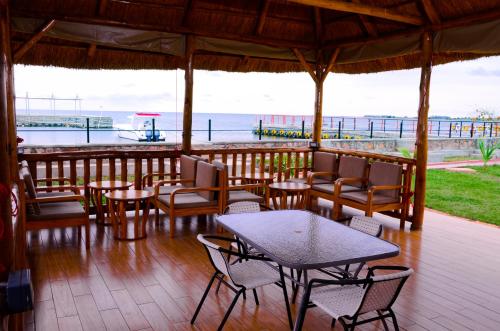 a patio with tables and chairs and a view of the ocean at Pelican Lodge & Marina in Entebbe