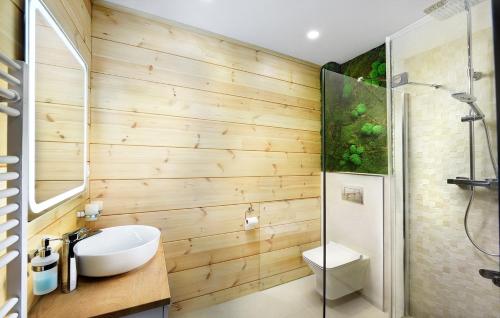 uma casa de banho com paredes de madeira, um lavatório e um chuveiro em Vila Valentina em Veľká Lomnica
