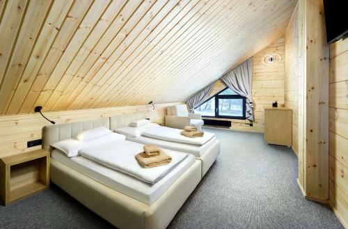 2 camas en una habitación con techo de madera en Vila Valentina en Veľká Lomnica