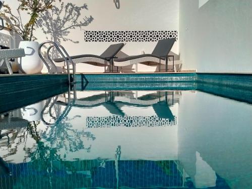 a swimming pool with two chairs sitting next to the water at Dar Shâan in Rabat